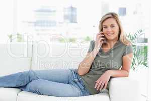 Woman lying across the couch, smiling, looking forward and makin