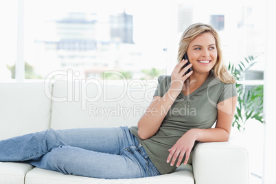 Woman lying on the couch, making a call, smiling and looking to