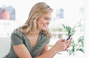 Woman smiles as she uses her phone while on the couch