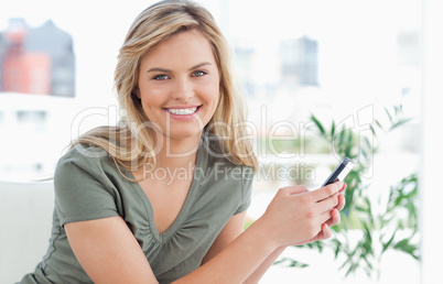 Woman looking forward smiling as she holds her phone