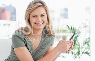 Woman looking forward smiling as she holds her phone