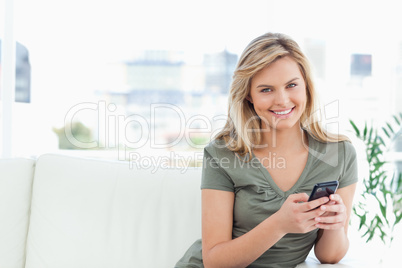 Woman looking straight ahead and smiling as she uses her phone