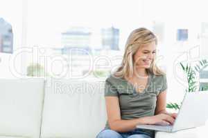Woman using her laptop on the couch and smiling