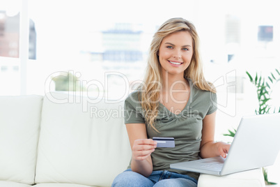 Woman looking ahead and smiles as she holds her credit card, and