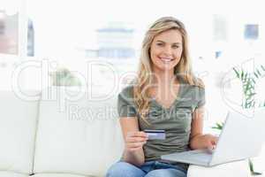 Woman looking ahead and smiles as she holds her credit card, and