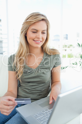 Woman looking at her laptop screen while holding her credit card