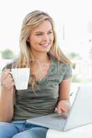 Woman looking slightly to the side, as she holds a cup in her ha