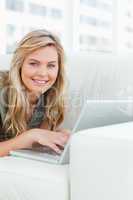 Close up, woman smiling as she looks forward, using her laptop