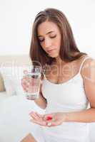 Woman looking down at the two pills she is going to take with wa