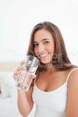 Woman smiling as she raises a glass near to her mouth