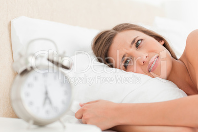Woman looking agitated by her alarm clock