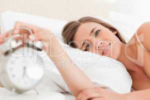 Woman looking forward as she silences her alarm clock