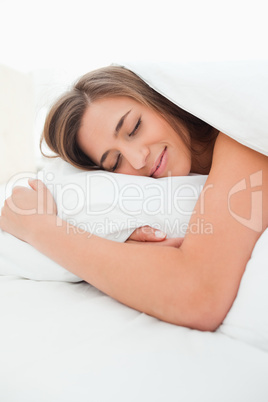 Close up, woman in bed, hand under pillow and smiling