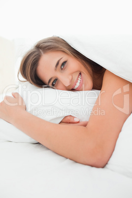 Woman lying in bed, awake, smiling as she looks forward