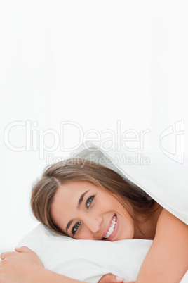 Vertical shot, woman in bed, awake, smiling while looking ahead