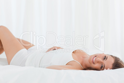 Woman lying on the bed on her back, smiling and looking forward