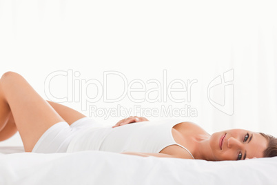 Woman lying on the bed on her back, looking straight ahead