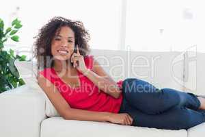 Woman on the couch, smiling while making a phone call and lookin