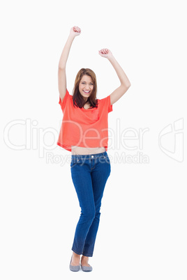 Laughing teenage wearing casual clothes while raising her arms