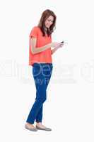 Teenage girl standing upright while sending a text