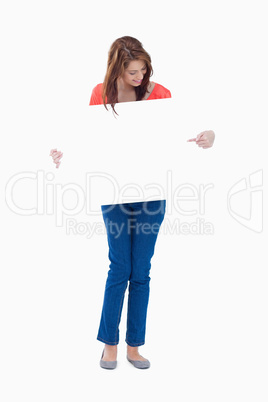 Smiling teenager holding a blank poster while pointing at it