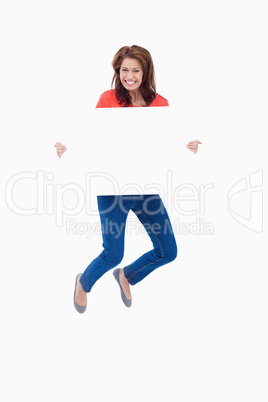 Excited teenager jumping while holding a blank poster