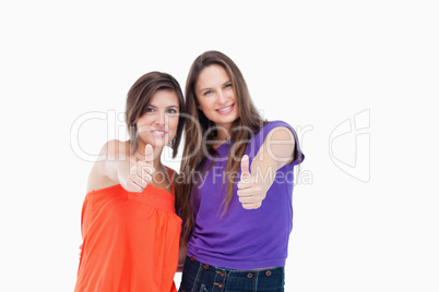 Two teenagers putting their thumbs up while smiling