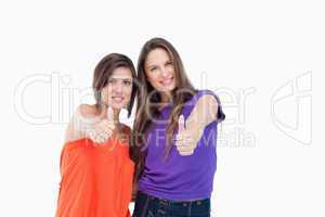 Two teenagers putting their thumbs up while smiling