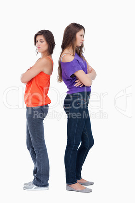 Two girls standing back to back with their arms crossed