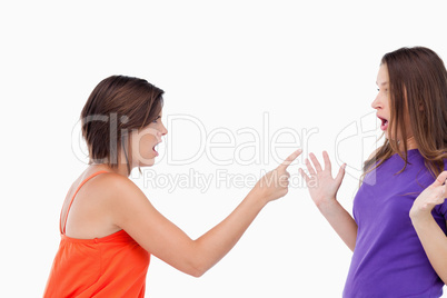 Teenage girl harshly pointing her finger at her surprised friend