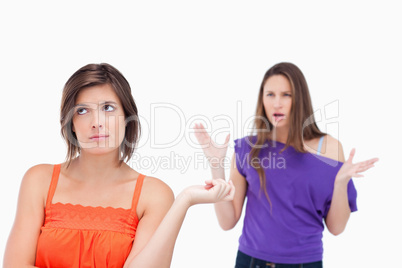 Exasperated teenager standing upright while her friend is roarin