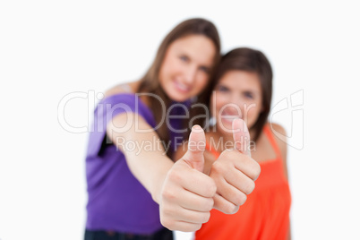 Thumbs up being showed by two friends while standing side by sid