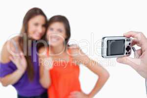 Two teenage girls photographed by a friend holding a digital cam