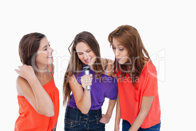 Teenage girls energetically singing in a microphone