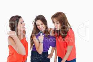 Teenage girls energetically singing in a microphone