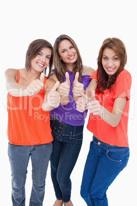 Teenage girls showing their happiness by putting their thumbs up