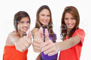 Smiling teenagers showing their approval by putting their thumbs