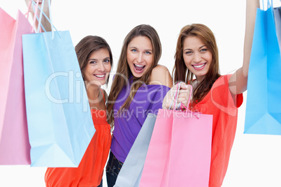 Three teenagers raising their arms while holding their purchases