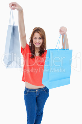 Teenage girl smiling and raising her shopping bags in the air