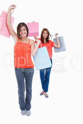 Smiling teenagers holding purchase bags in the air