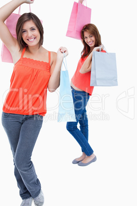 Smiling teenage girl followed by a friend and both are holding p