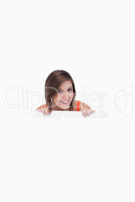 Smiling teenage girl standing behind a blank poster