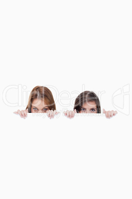 Two friends secretly hiding behind a blank poster