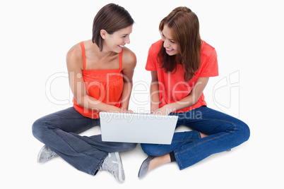 Smiling teenagers sitting cross-legged with a laptop