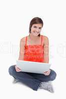 Beautiful teenage sitting cross-legged with a laptop on her legs