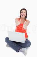 Teenage laughing with her thumbs up while sitting cross-legged