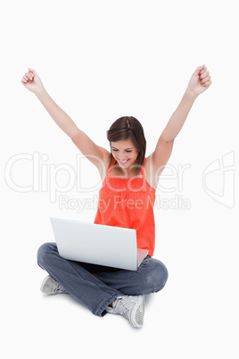 Teenager showing her satisfaction behind her laptop while raisin
