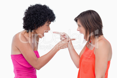 Angry teenage girls standing face to face and pointing their fin