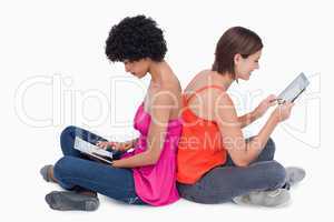 Teenage girl holding her tablet PC in the air while a friend is