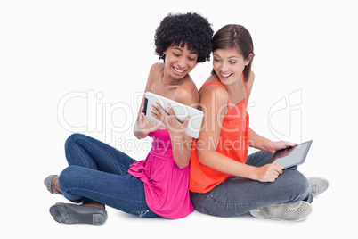 Laughing teenagers looking at a tablet PC while sitting cross-le